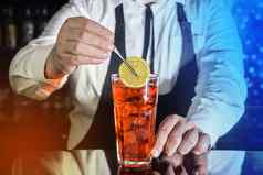 专业酒保把片柠檬红色的冷冻含酒精的鸡尾酒酒吧镊子玻璃夜总会计数器