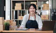肖像年轻的亚洲女人电子商务员工坐着办公室完整的包背景写请注意订单计算器锻造业务电子商务交付业务
