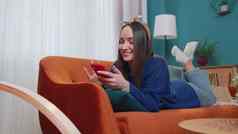 快乐的年轻的女人说谎沙发移动电话分享消息社会媒体应用程序