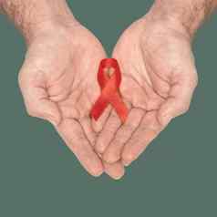 红色的意识丝带弓男人帮助手孤立的绿色背景艾滋病毒艾滋病世界一天社会生活问题概念艾滋病慈善机构基金概念医疗保健医学概念