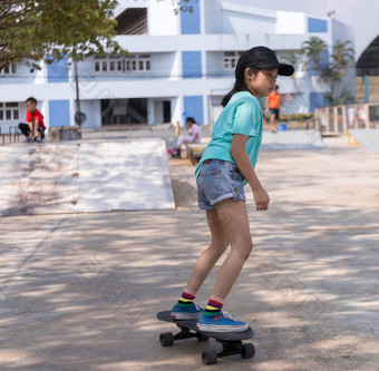 亚洲女孩玩冲浪滑冰董事会公园滑冰斜坡在户外早....快乐女孩玩冲浪溜冰董事会公园体育运动活动生活方式概念