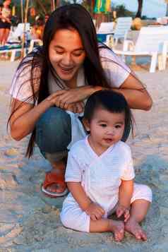 快乐家庭妈妈。女儿玩海滩快乐女孩放松坐海滩妈妈。微笑妈妈。玩女儿