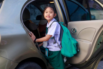 亚洲学校女孩穿学校统一的携带绿色背包公共汽车学校早....快乐主学校孩子车家庭车运输概念