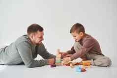 爸爸儿子微笑有趣的玩彩色的砖玩具白色背景亲子鉴定有爱心的父亲孩子