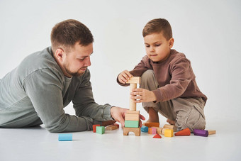 亲子鉴定儿子爸爸玩彩色的砖玩具白色背景父亲需要护理孩子