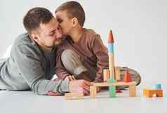 英俊的儿子接吻父亲亲子鉴定爸爸儿子玩彩色的木块白色背景