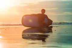 轮廓冲浪男人。坐着冲浪板海滨海滩日落时间
