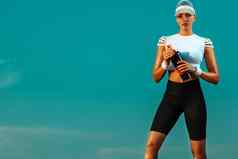 女跑步者站在户外持有水瓶女人采取打破运行锻炼运动适合女孩运动员放松瑜伽天空背景概念健康的生活方式体育运动