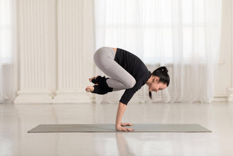 美丽的年轻的亚洲女人工作在室内瑜伽锻炼倒立体式起重机乌鸦构成巴卡萨纳
