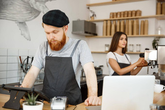 咖啡业务概念年轻的英俊的有胡子的酒保咖啡师经理发布订单客人数字平板电脑菜单现代咖啡商店