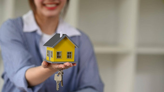 微笑女金融顾问手持有房子模型键房子保险真正的房地产概念