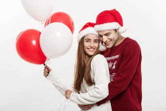 圣诞节概念年轻的女朋友持有气球拥抱玩的男朋友惊喜圣诞节