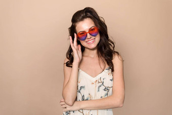 美丽的有吸引力的时尚的女人夏天衣服心眼镜相机提出了米色背景夏天时尚风格自然