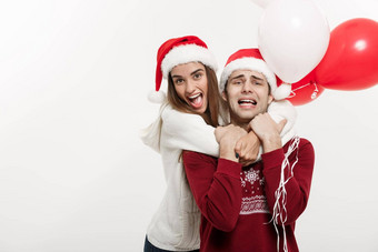 圣诞节概念年轻的女朋友持有气球拥抱玩的男朋友惊喜圣诞节