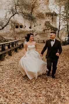婚礼夫妇爱男人。女人运行快乐秋天森林背景石头岩石