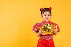 快乐亚洲中国人女孩微笑穿红色的旗袍持有大黄金锭