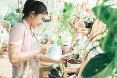 年轻的女人植物老板商店浇水植物植物商店