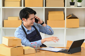 年轻的亚洲男人。会说话的移动电话确认订单客户在线销售电子商务概念