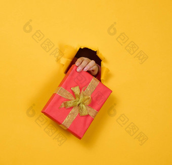 女手持有盒子礼物黄色的背景部分身体棒撕裂洞纸背景祝贺假期惊喜