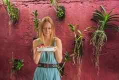年轻的女人地中海早餐吃健康的热带早餐奶昔碗热带水果装饰模式色彩斑斓的酸奶姜黄螺旋藻装饰水果花传讲种子椰子格兰诺拉麦片菠萝薄荷草莓