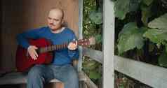 男人。声吉他坐着玄关房子玩仪器