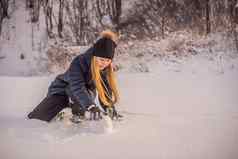 年轻的女人滚动巨大的雪球使雪人