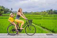 妈妈。儿子骑自行车大米场乌布巴厘岛旅行巴厘岛孩子们概念