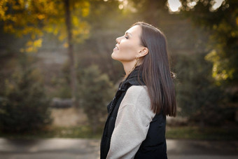 配置文件年轻的沉思的女人秋天公园在户外米色夹克黑色的无袖夹克