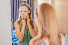 年轻的红发女人面部面具表美皮肤护理概念