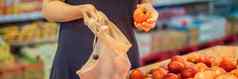 女人选择西红柿超市塑料袋可重用的袋购买蔬菜浪费概念横幅长格式