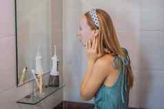 年轻的红发女人面部面具表美皮肤护理概念