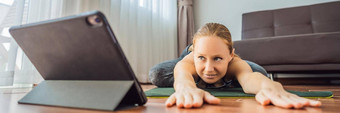 健身女人锻炼地板上首页看<strong>健身视频</strong>平板电脑人体育在线coronovirus横幅长格式