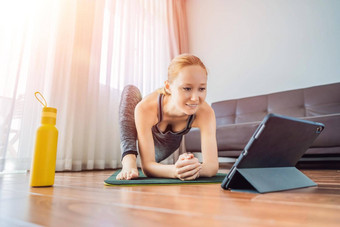 健身女人锻炼地板上首页看<strong>健身视频</strong>平板电脑人体育在线coronovirus
