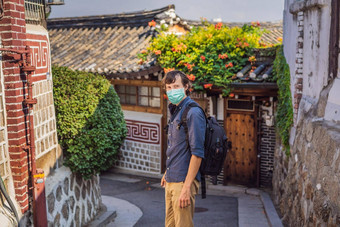 年轻的男人。旅游医疗面具北村韩屋村著名的的地方朝鲜文传统的房子保存旅行韩国概念游客恐惧法律顾问病毒医疗戴面具的游客