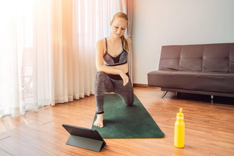健身女人锻炼地板上首页看健身视频平板电脑人体育在线coronovirus