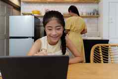 自主学习亚洲妈妈。年轻的女孩学生学习在线类电子学习在线教育概念