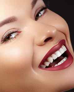 时尚女人脸完美的微笑女模型光滑的皮肤长睫毛红色的嘴唇健康的白色牙齿