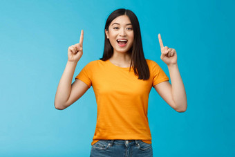 逗乐亚洲女孩介绍产品分享促销提高手指出手指微笑广泛的兴奋乐观的热情的广告站蓝色的背景