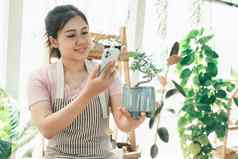 微笑年轻的女人采取智能手机图片植物小商店
