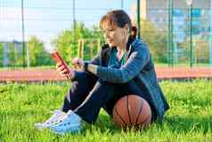 活跃的成熟的女人篮球球智能手机户外