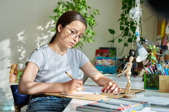 十几岁的有<strong>创意</strong>的女孩艺术家画铅笔坐着<strong>表格</strong>首页