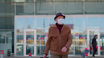 高级养老金领取者旅游祖父穿保护脸面具避免冠状病毒机场
