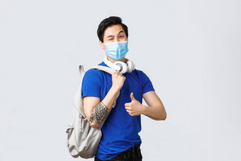 回来学校研究科维德教育大学生活概念英俊的赶时髦的人的家伙亚洲大一新生学生医疗面具显示翘拇指头类背包耳机