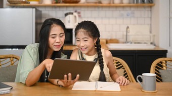 有爱心的亚洲妈妈。帮助女儿家庭作业概念虚拟教育在家教育