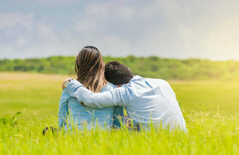 夫妇爱坐着草拥抱回来浪漫的夫妇坐着草拥抱回来后视图夫妇爱拥抱草