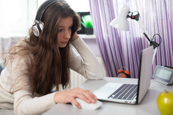 年轻的浅黑肤色的女人在家教育远程互联网移动PC