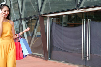 女人会说话的智能手机持有购物袋消费主义生活方式购物中心