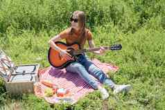 年轻的女人玩吉他野餐