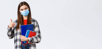 冠状病毒流感大流行科维德教育回来学校概念很高兴年轻的女大一新生大学显示翘拇指研究声望大学携带笔记本电脑