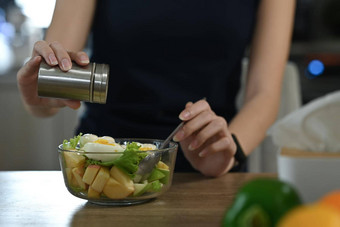 女人添加盐健康的<strong>蔬菜</strong>沙拉<strong>玻璃碗</strong>健康的生活方式概念